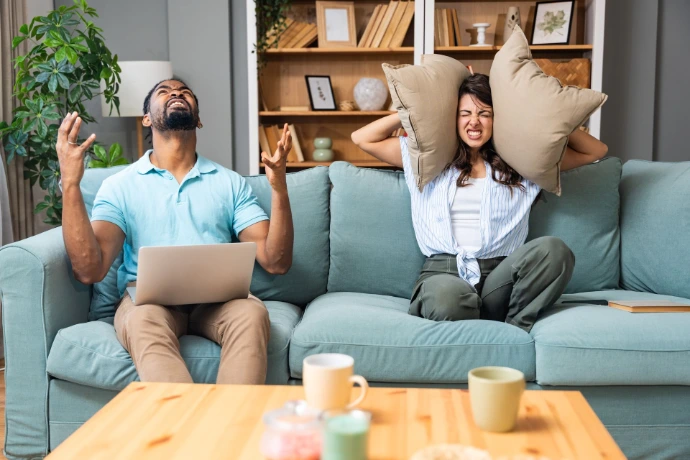 Deux personnes dans un salon dérangées par le bruit des boisins
